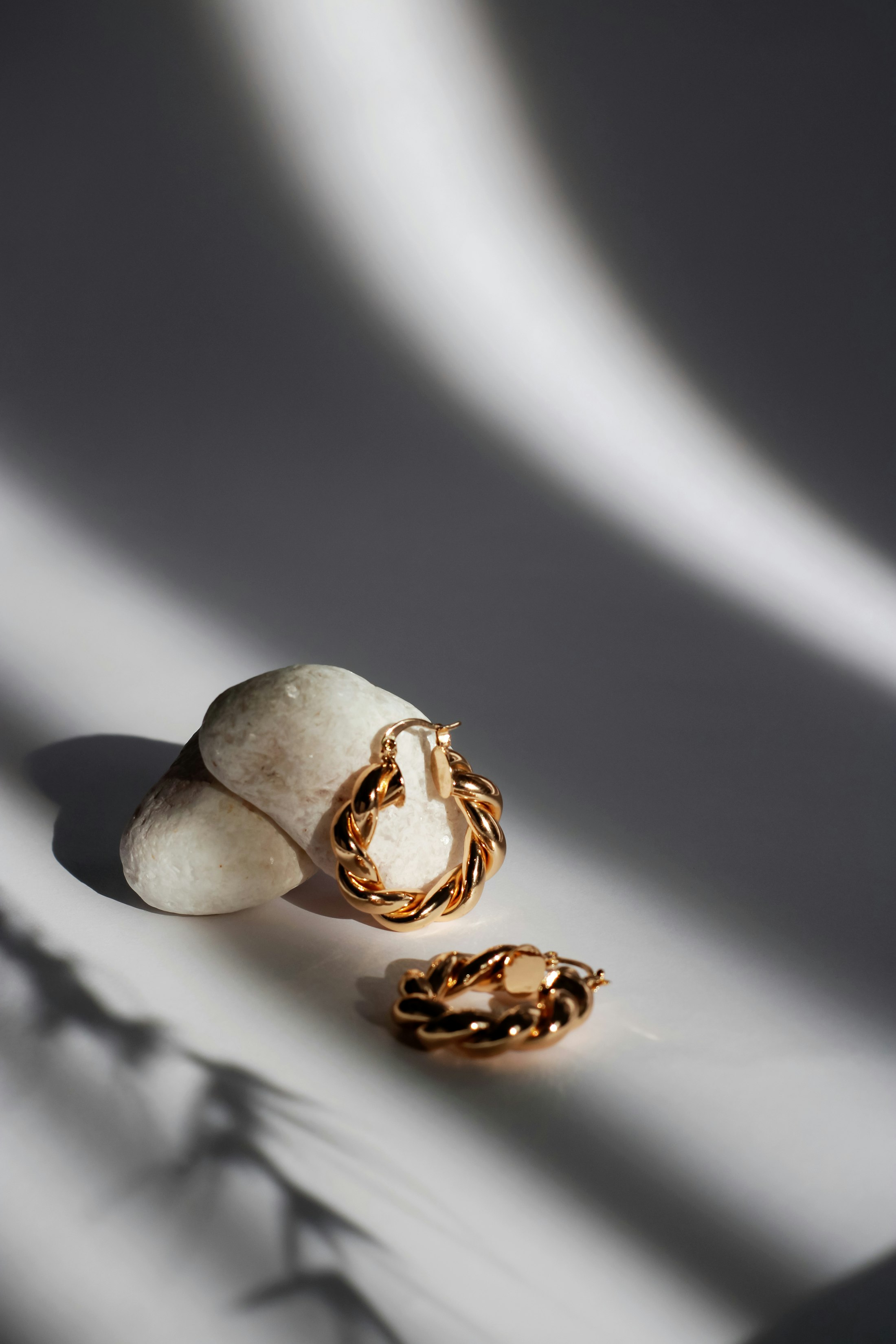 Bijoux en or posés sur un drapé, dans une lumière rasante