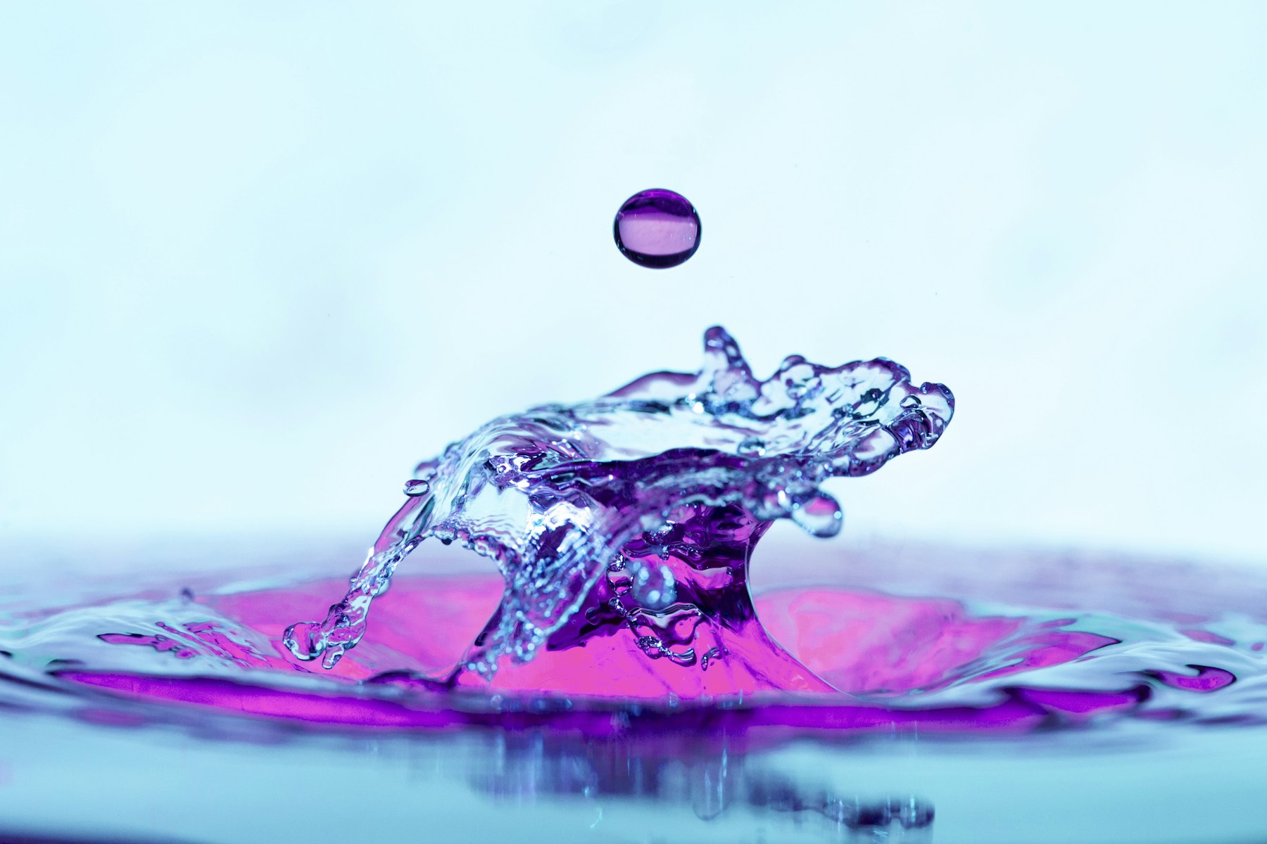 Goutte violette suspendue au-dessus d'une éclaboussure